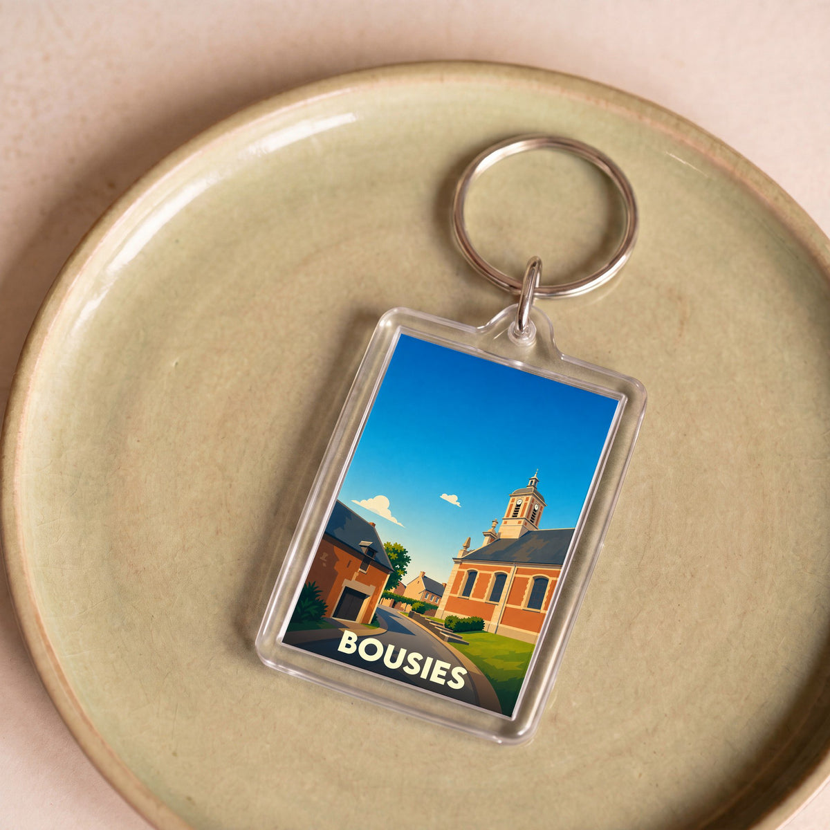 Porte-clés souvenir de la ville de Bousies avec une illustration stylisée de son église.