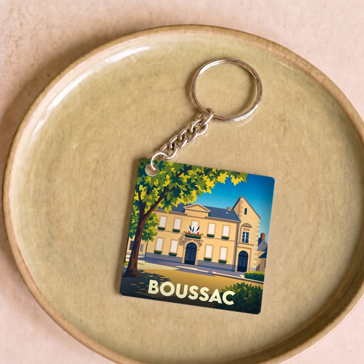 Porte-clés souvenir de la ville de Boussac avec une illustration stylisée.
