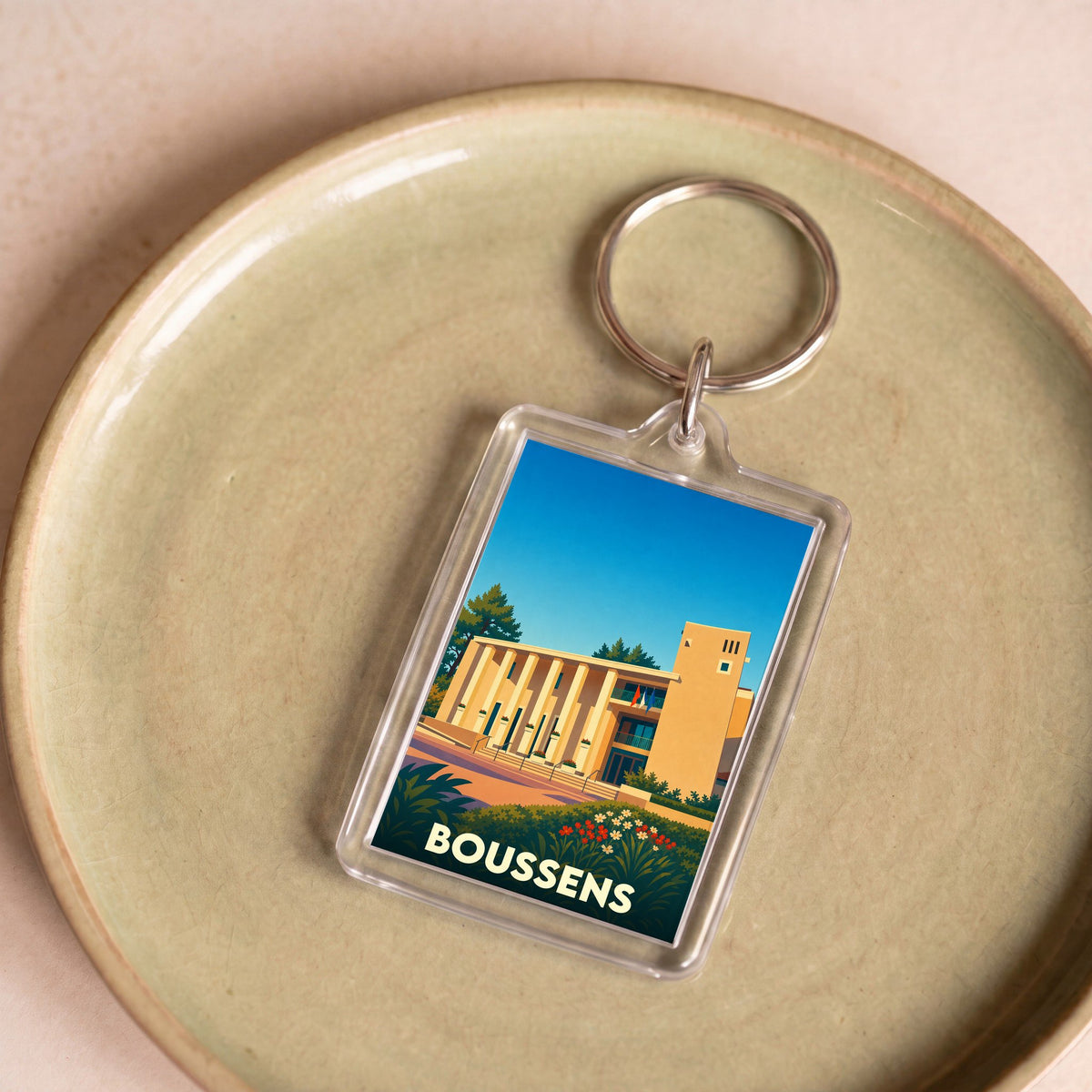 Porte-clés souvenir de la ville de Boussens avec une illustration stylisée.