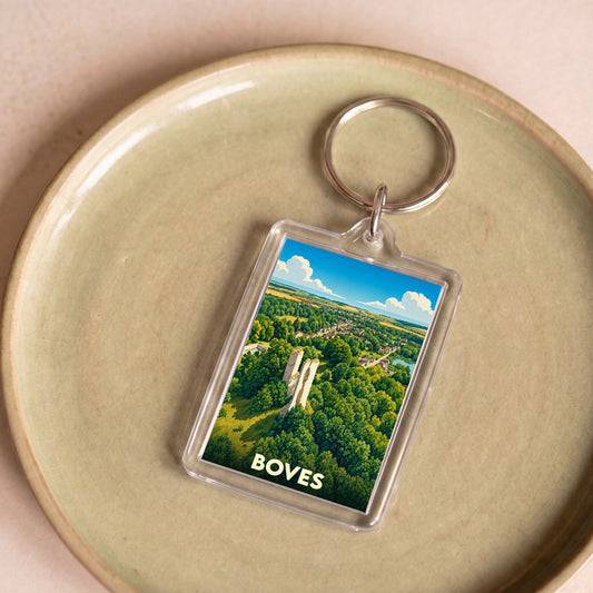 Porte-clés souvenir de la ville de Boves avec une illustration stylisée de son château et de sa forêt.