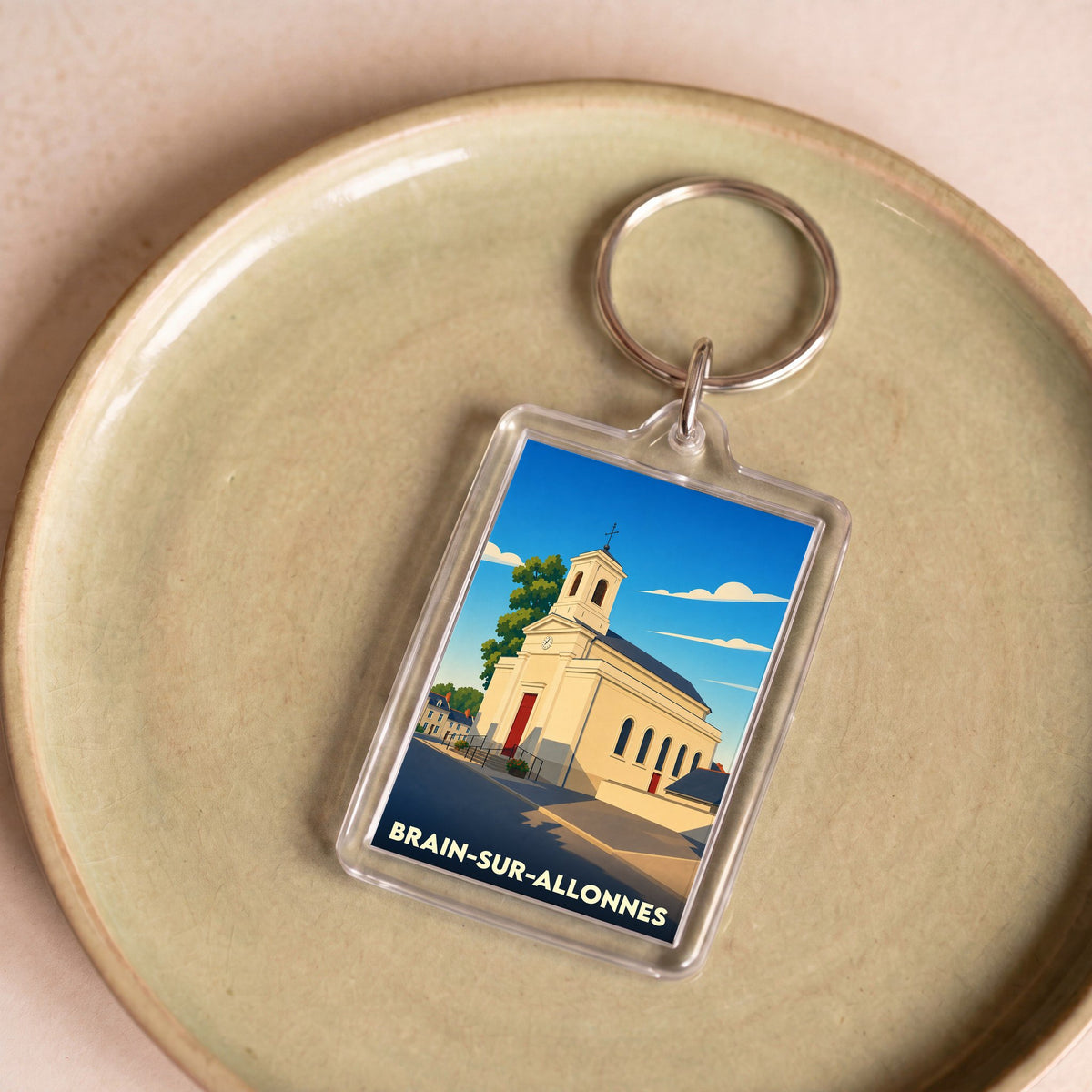 Porte-clés souvenir de la ville de Brain-sur-Allonnes avec une illustration stylisée de son église.