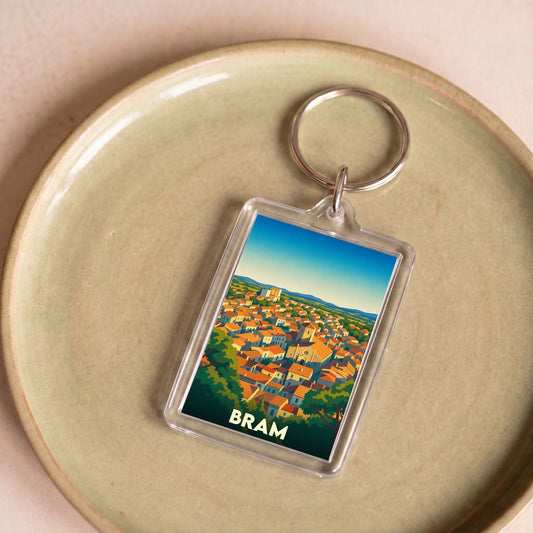 Porte-clés souvenir de la ville de Bram avec une illustration stylisée de ses toits orangés.