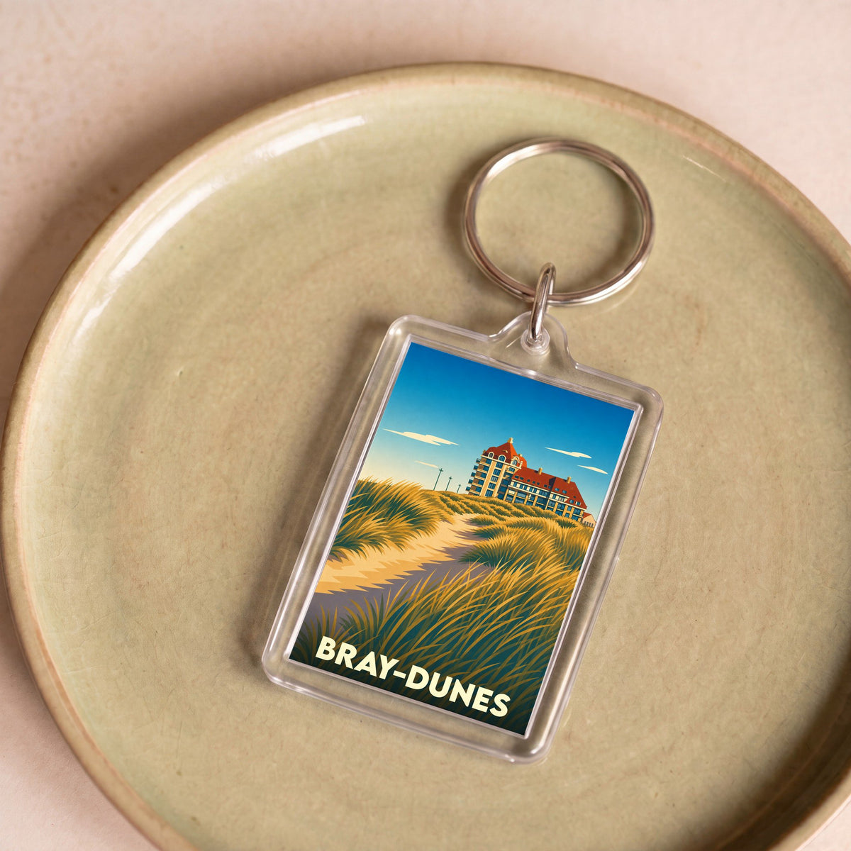 Porte-clés souvenir de la ville de Bray-Dunes avec une illustration stylisée de ses dunes et de son architecture.
