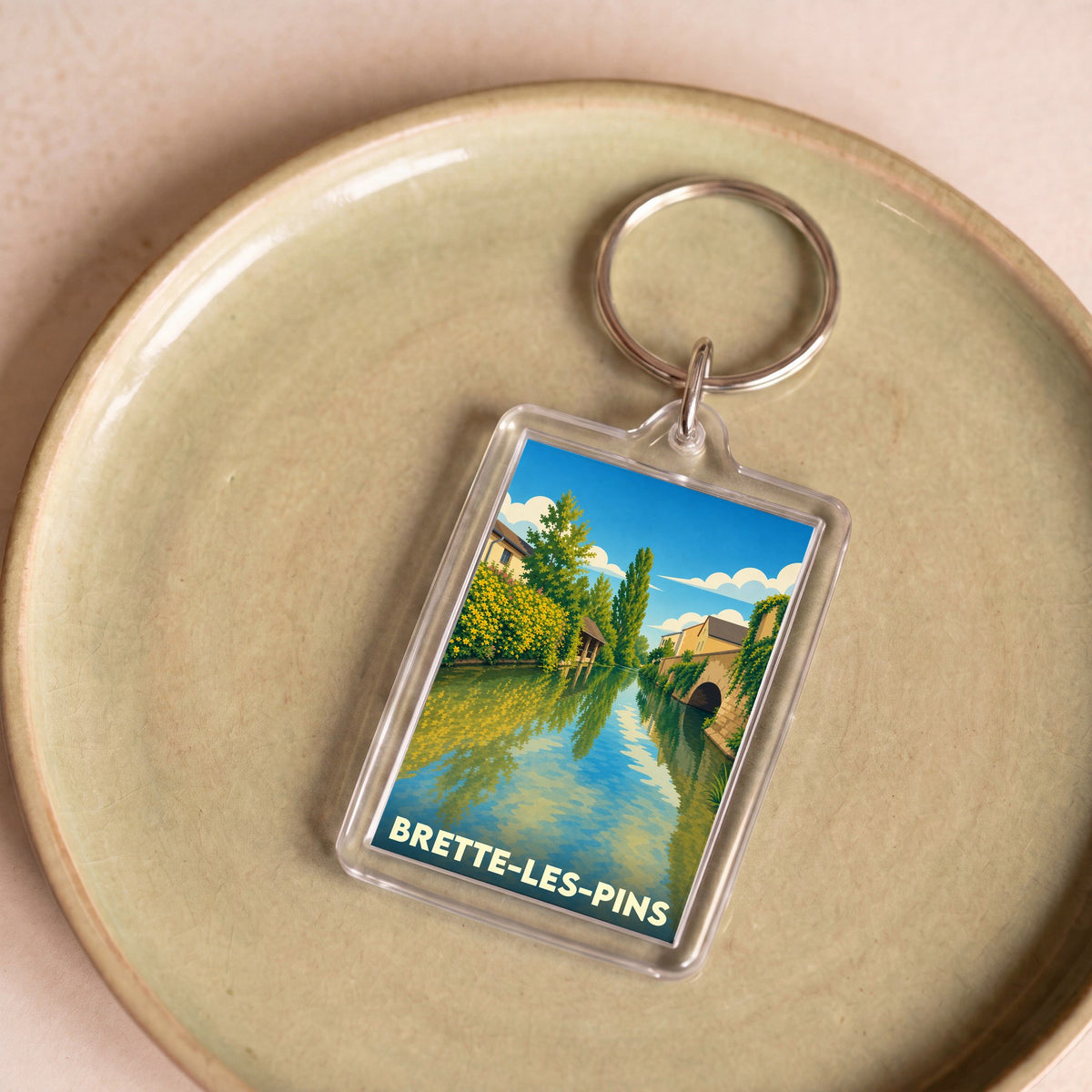 Porte-clés souvenir de la ville de Brette-les-Pins avec une illustration stylisée d'un canal.