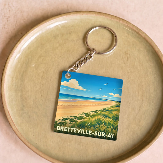 Porte-clés souvenir de Bretteville-sur-Ay avec une illustration stylisée de sa plage et de ses dunes.