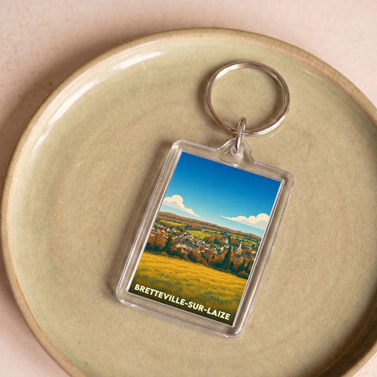 Porte-clés souvenir de Bretteville-sur-Laize avec une illustration stylisée de la ville et de ses paysages.