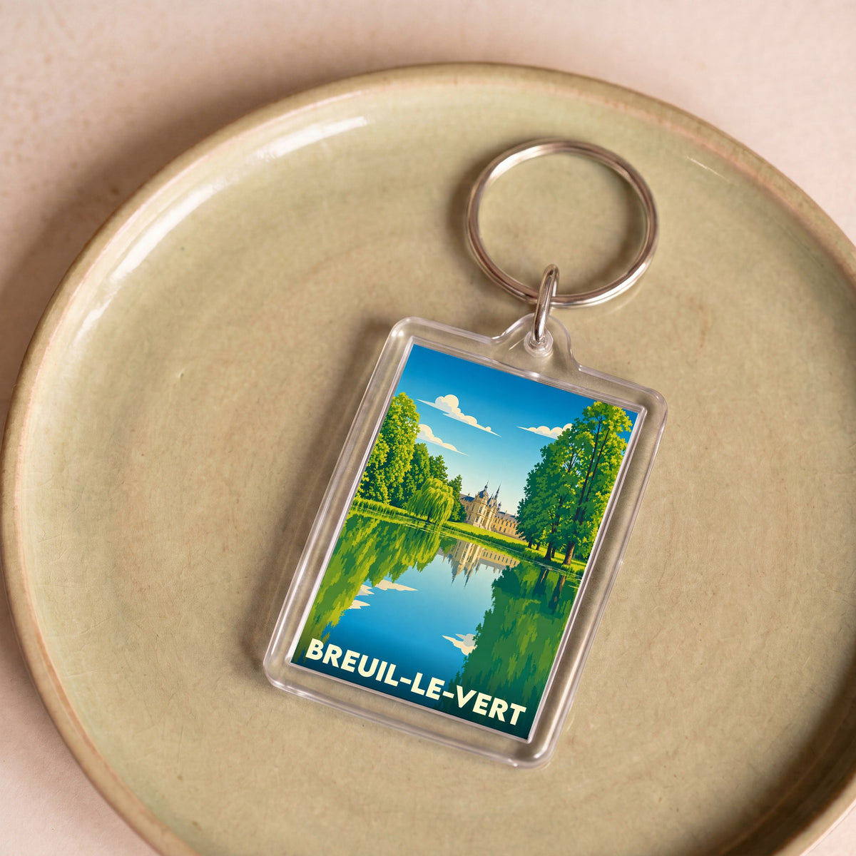 Porte-clés souvenir de la ville de Breuil-le-Vert avec une illustration stylisée d'un château se reflétant dans l'eau.