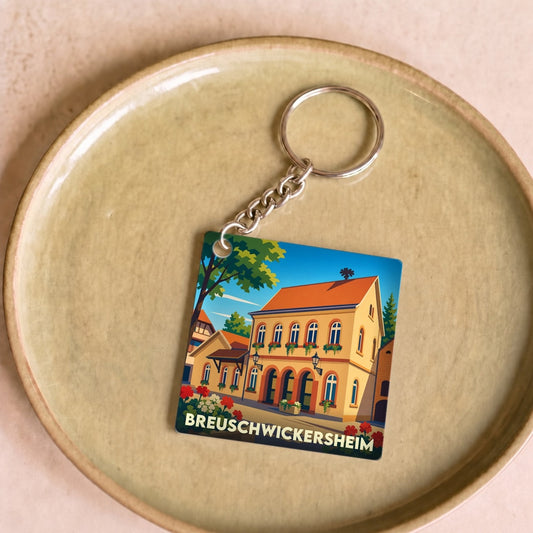 Porte-clés souvenir de la ville de Breuschwickersheim avec une illustration stylisée d'un bâtiment traditionnel.