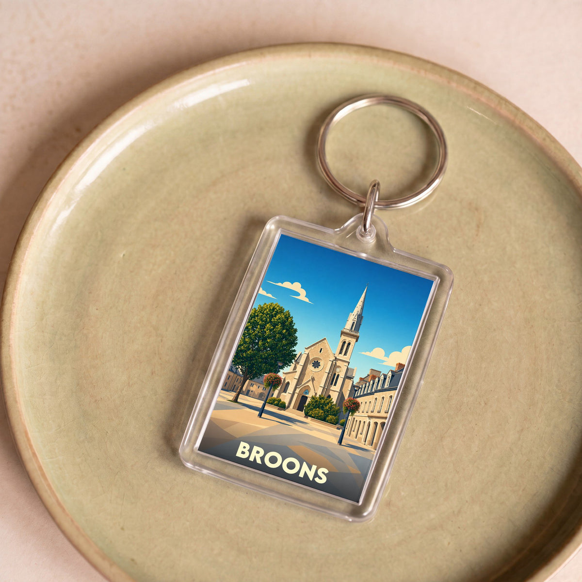 Porte-clés souvenir de la ville de Broons avec une illustration stylisée de son église.