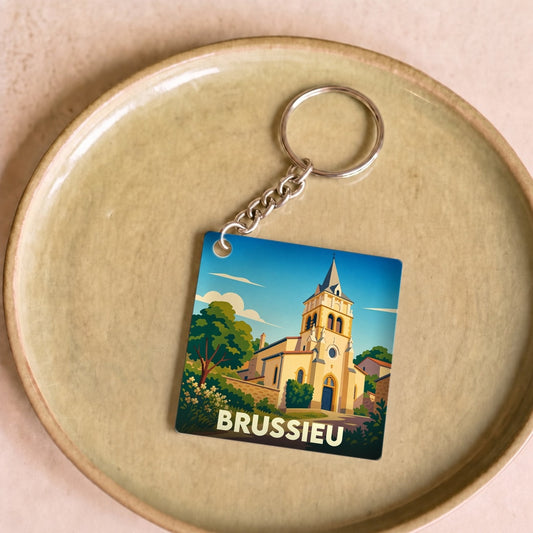 Porte-clés souvenir de la ville de Brussieu avec une illustration stylisée de son église.