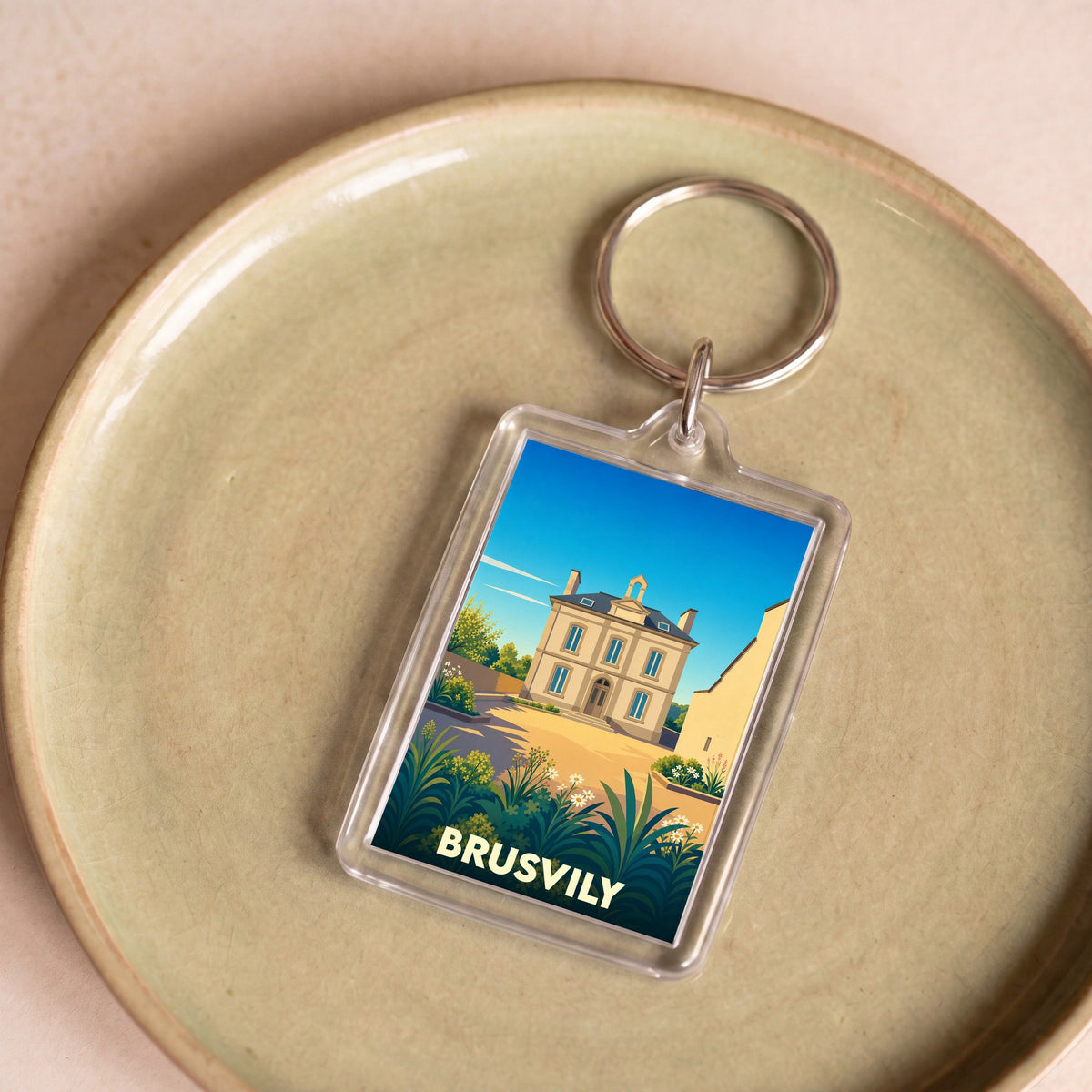 Porte-clés souvenir de la ville de Brusvily avec une illustration stylisée d'une bâtisse historique.