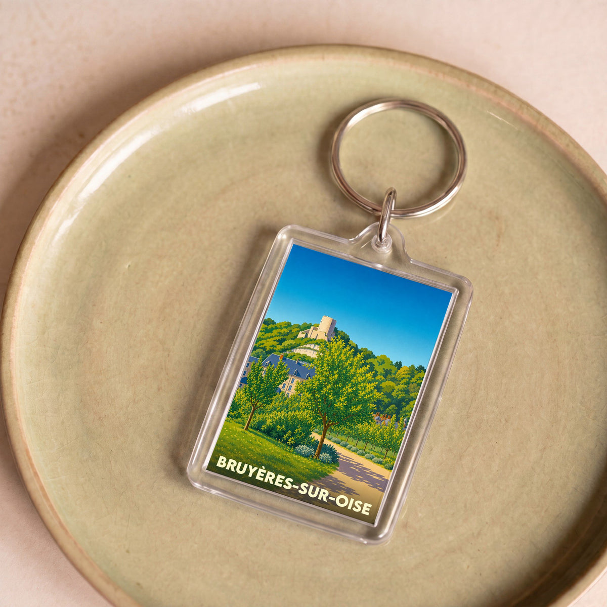 Porte-clés souvenir de la ville de Bruyères-sur-Oise avec une illustration stylisée d'un paysage verdoyant.