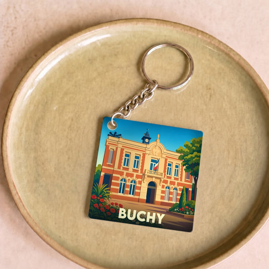 Porte-clés souvenir de la ville de Buchy avec une illustration stylisée de son hôtel de ville.