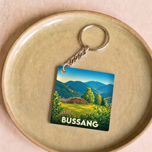 Porte-clés souvenir de la ville de Bussang avec une illustration de paysage montagneux.