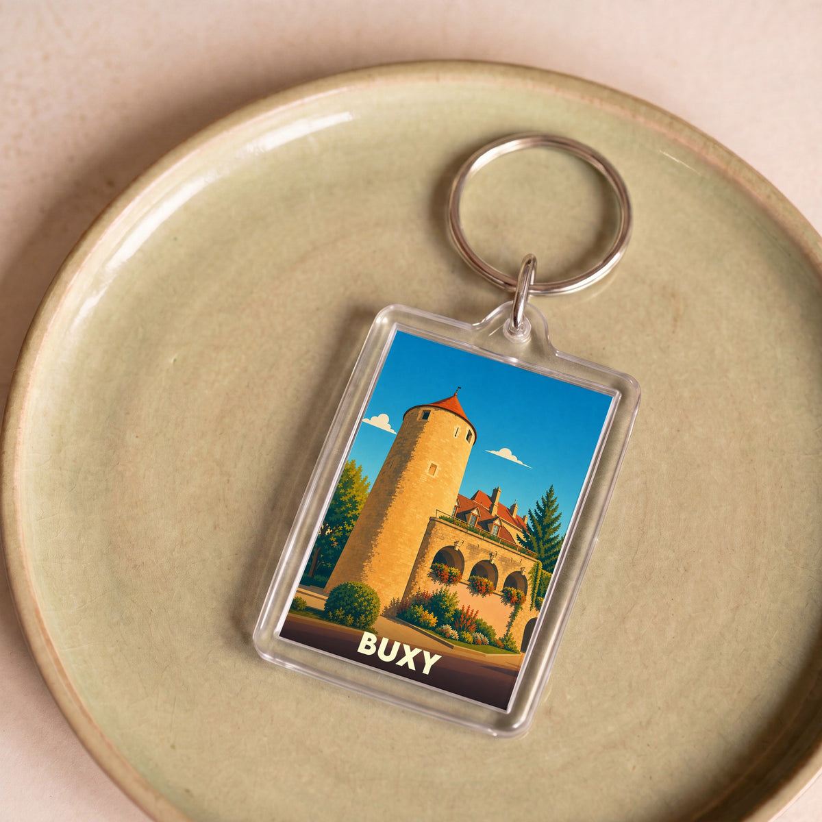 Porte-clés souvenir de la ville de Buxy avec une illustration stylisée d'une tour médiévale.