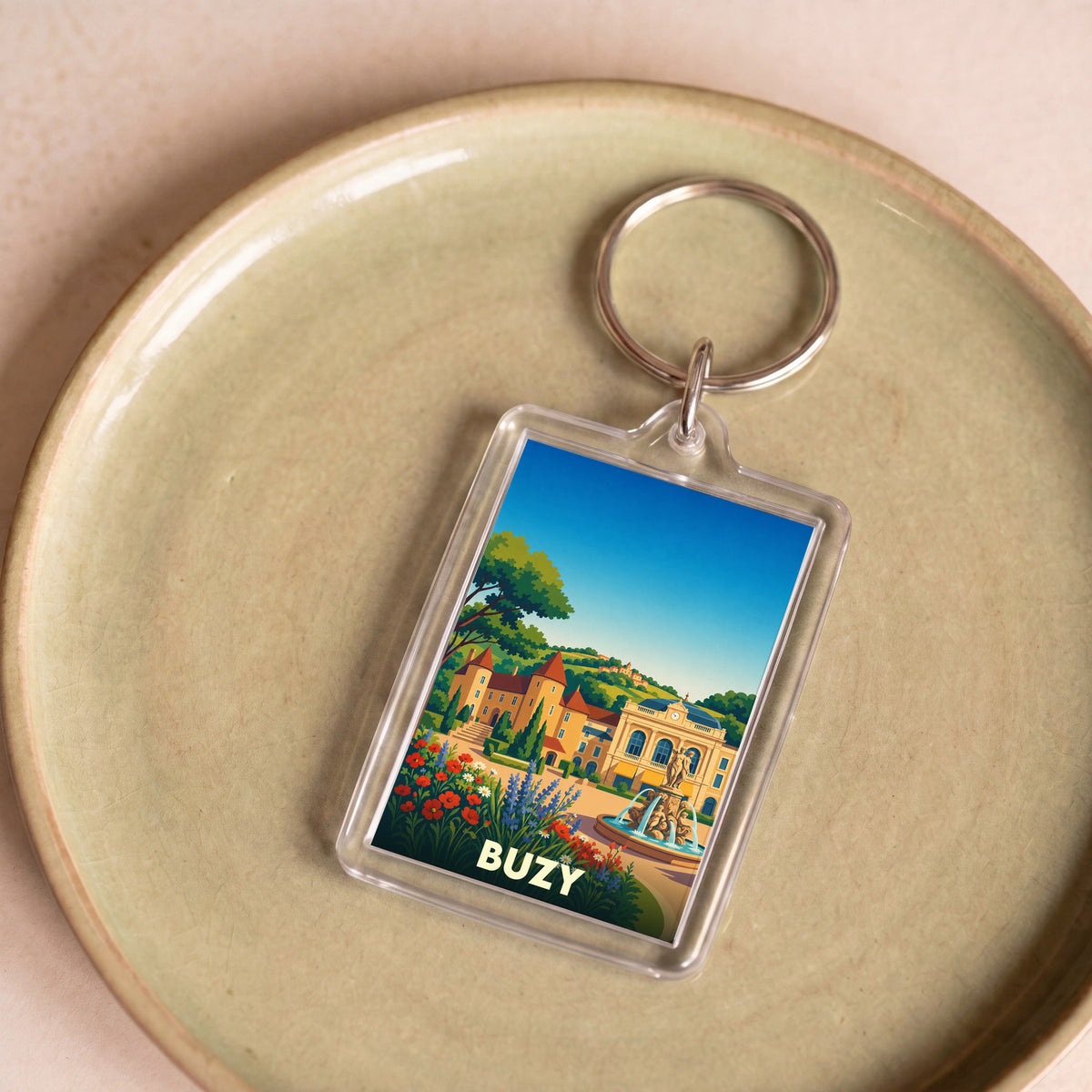 Porte-clés souvenir de la ville de Buzy avec une illustration stylisée et colorée de ses monuments.