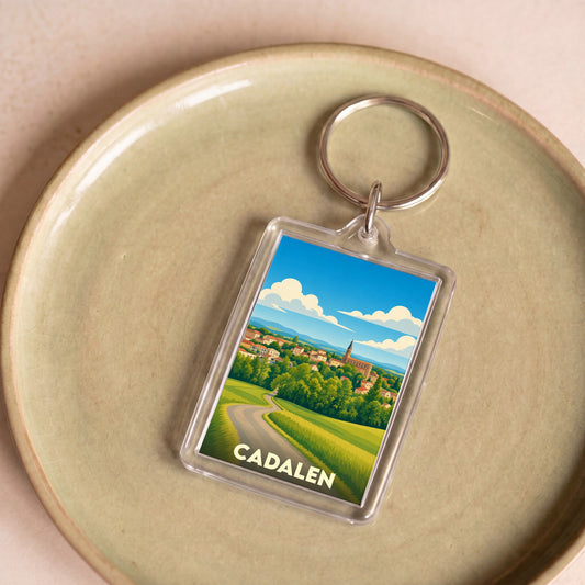 Porte-clés souvenir de la ville de Cadalen avec une illustration stylisée d'un paysage vallonné.