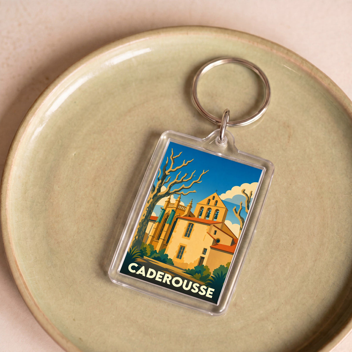 Porte-clés souvenir de la ville de Caderousse avec une illustration stylisée d'une église provençale.