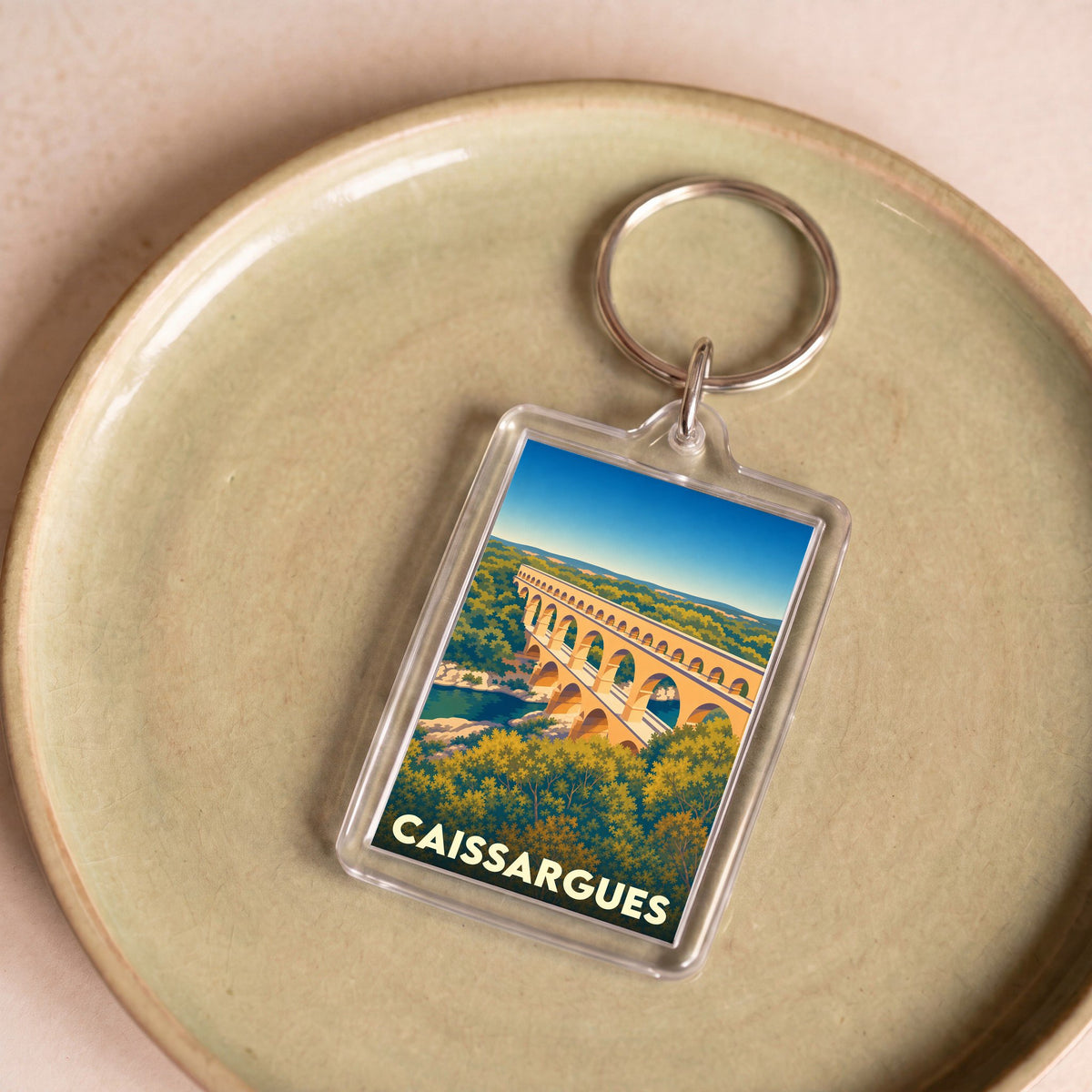 Porte-clés souvenir de la ville de Caissargues avec une illustration stylisée du Pont du Gard.