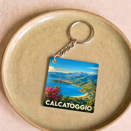 Porte-clés souvenir de la ville de Calcatoggio avec une illustration stylisée d'un paysage côtier.