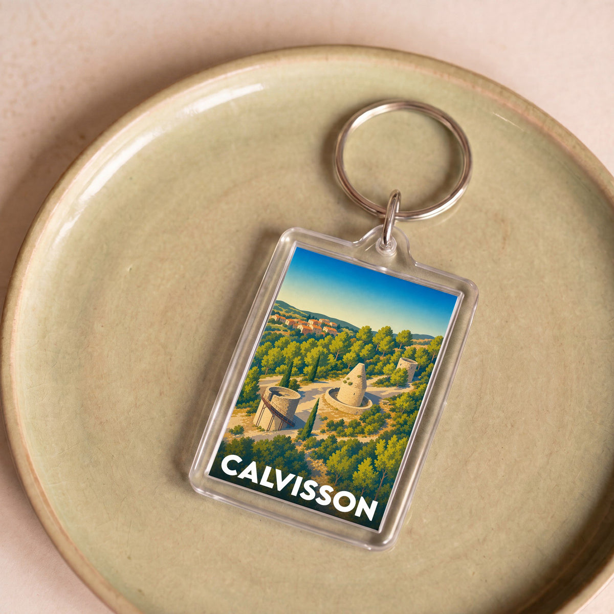 Porte-clés souvenir de la ville de Calvisson avec une illustration stylisée de son paysage et de ses moulins.