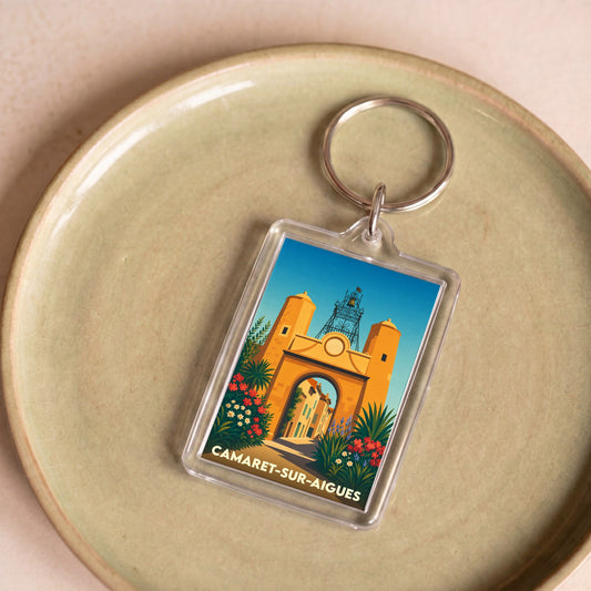 Porte-clés souvenir de la ville de Camaret-sur-Aigues avec une illustration stylisée de sa porte fortifiée.