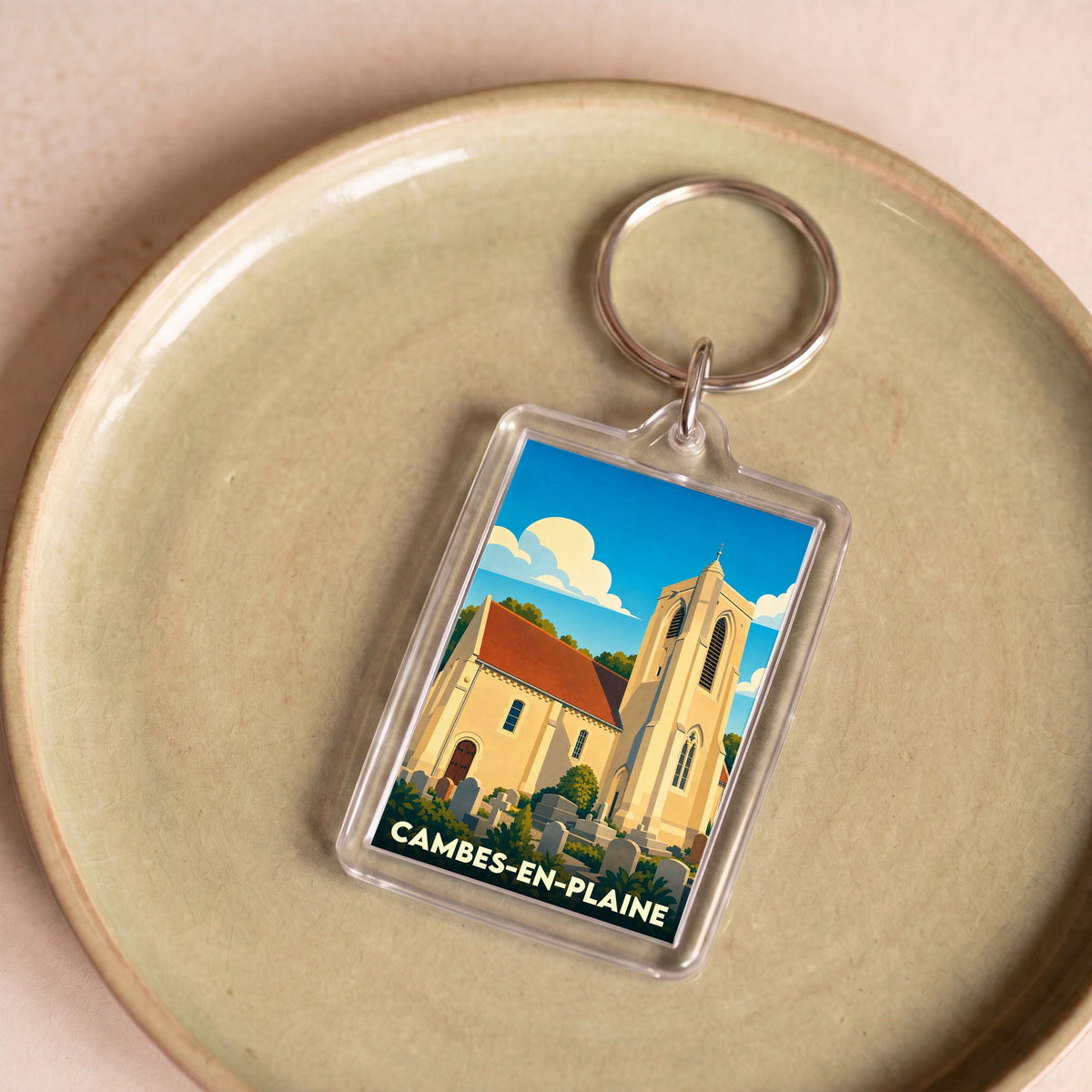 Porte-clés souvenir de la ville de Cambes-en-Plaine avec une illustration stylisée de son église.