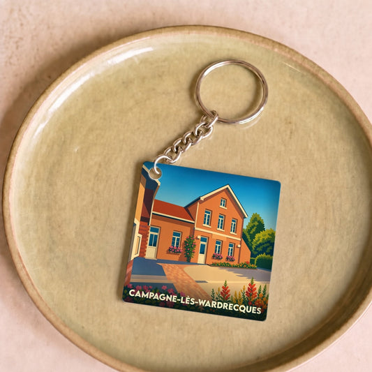 Porte-clés souvenir de la ville de Campagne-lès-Wardrecques avec une illustration stylisée d'une maison en briques.