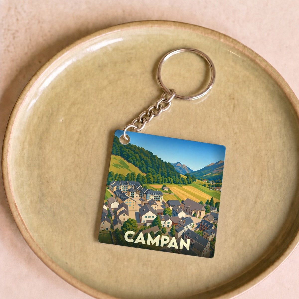 Porte-clés souvenir de la ville de Campan avec une illustration stylisée.