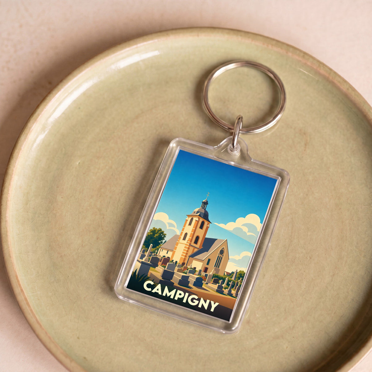 Porte-clés souvenir de la ville de Campigny avec une illustration stylisée d'une église et de son cimetière.