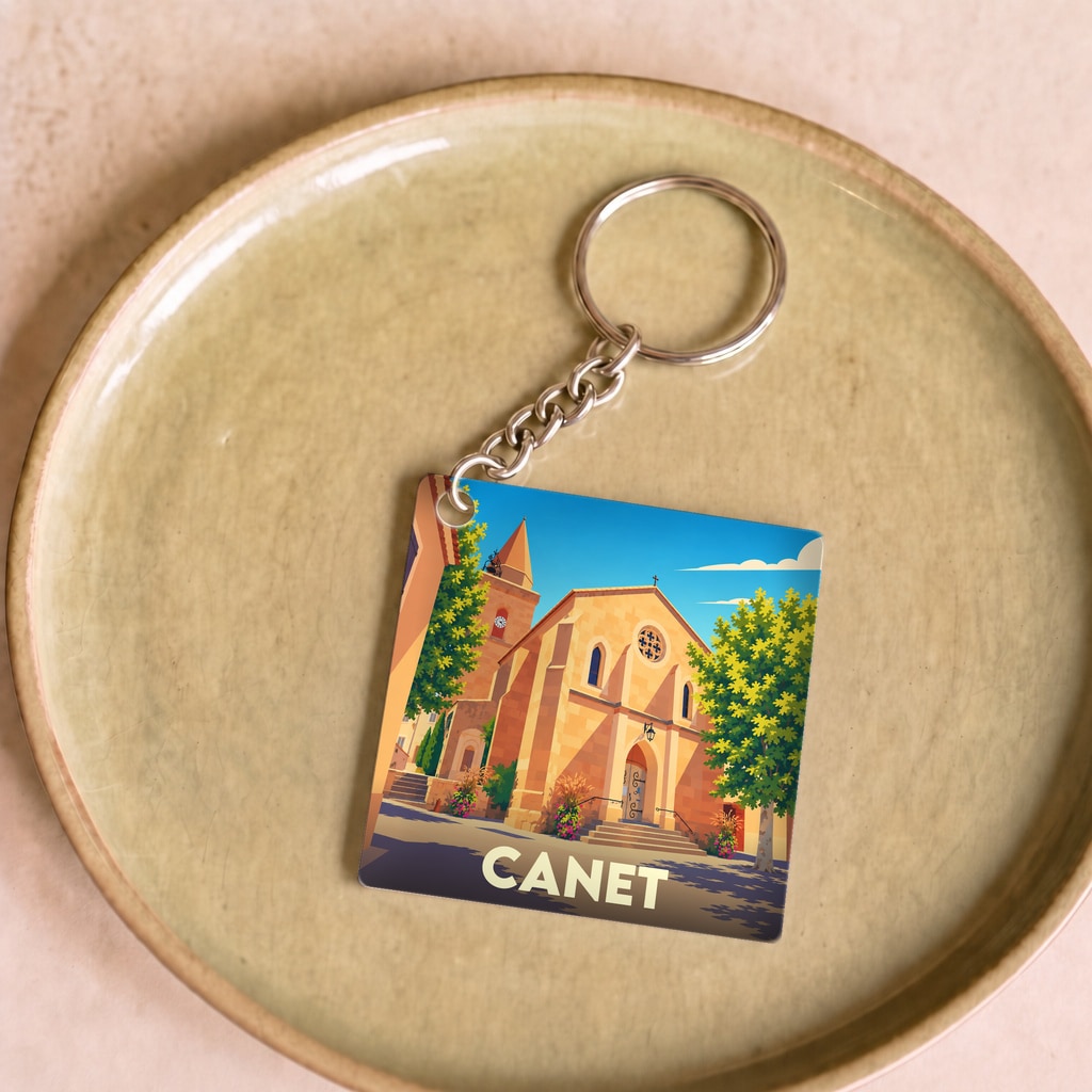 Porte-clés souvenir de la ville de Canet avec une illustration stylisée de son église sous un ciel bleu.