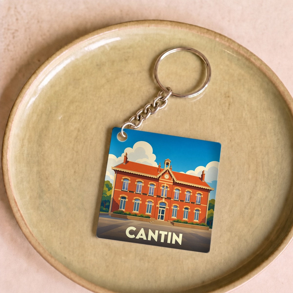 Porte-clés souvenir de la ville de Cantin avec une illustration stylisée d'un bâtiment en briques rouges.