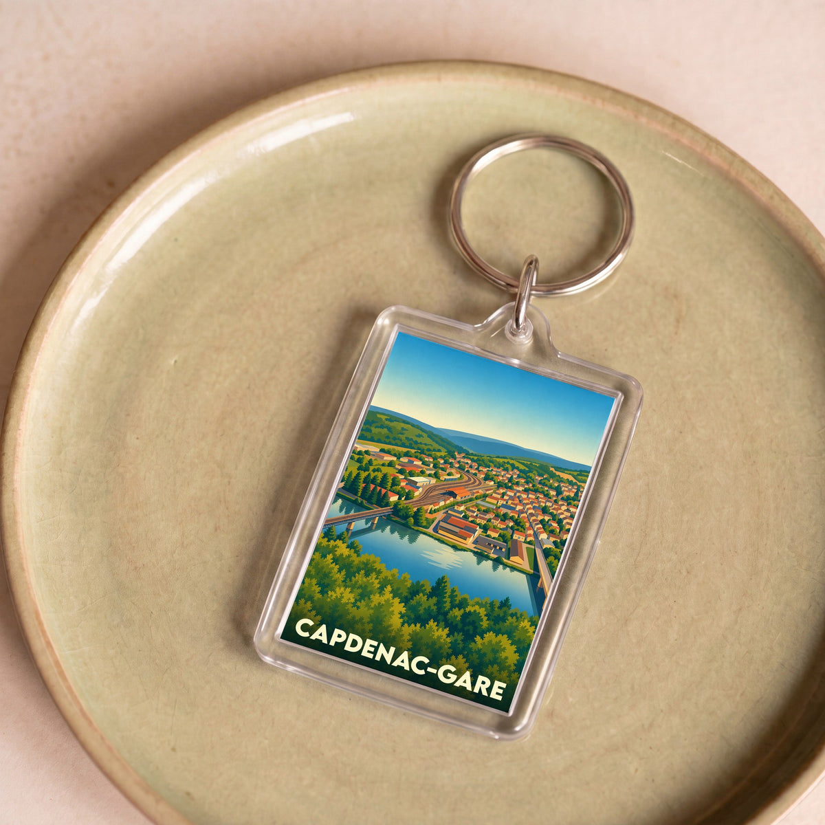 Porte-clés souvenir de Capdenac-Gare avec une illustration stylisée de la ville et de sa rivière.