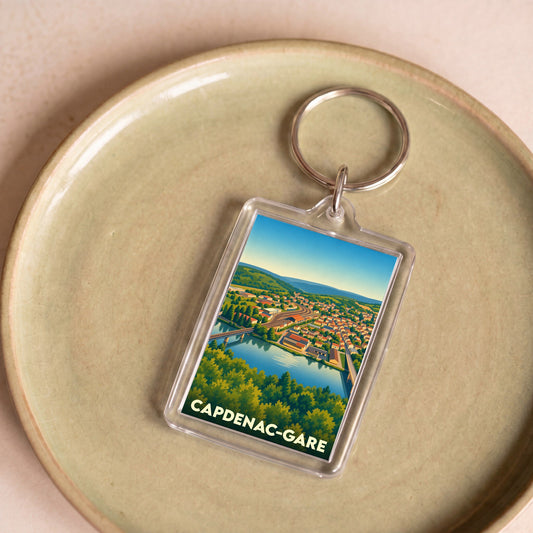 Porte-clés souvenir de Capdenac-Gare avec une illustration stylisée de la ville et de sa rivière.
