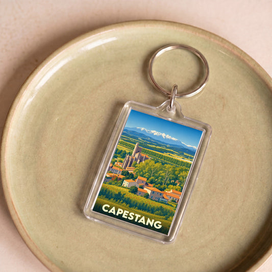 Porte-clés souvenir de la ville de Capestang avec une illustration stylisée d'un paysage provençal.
