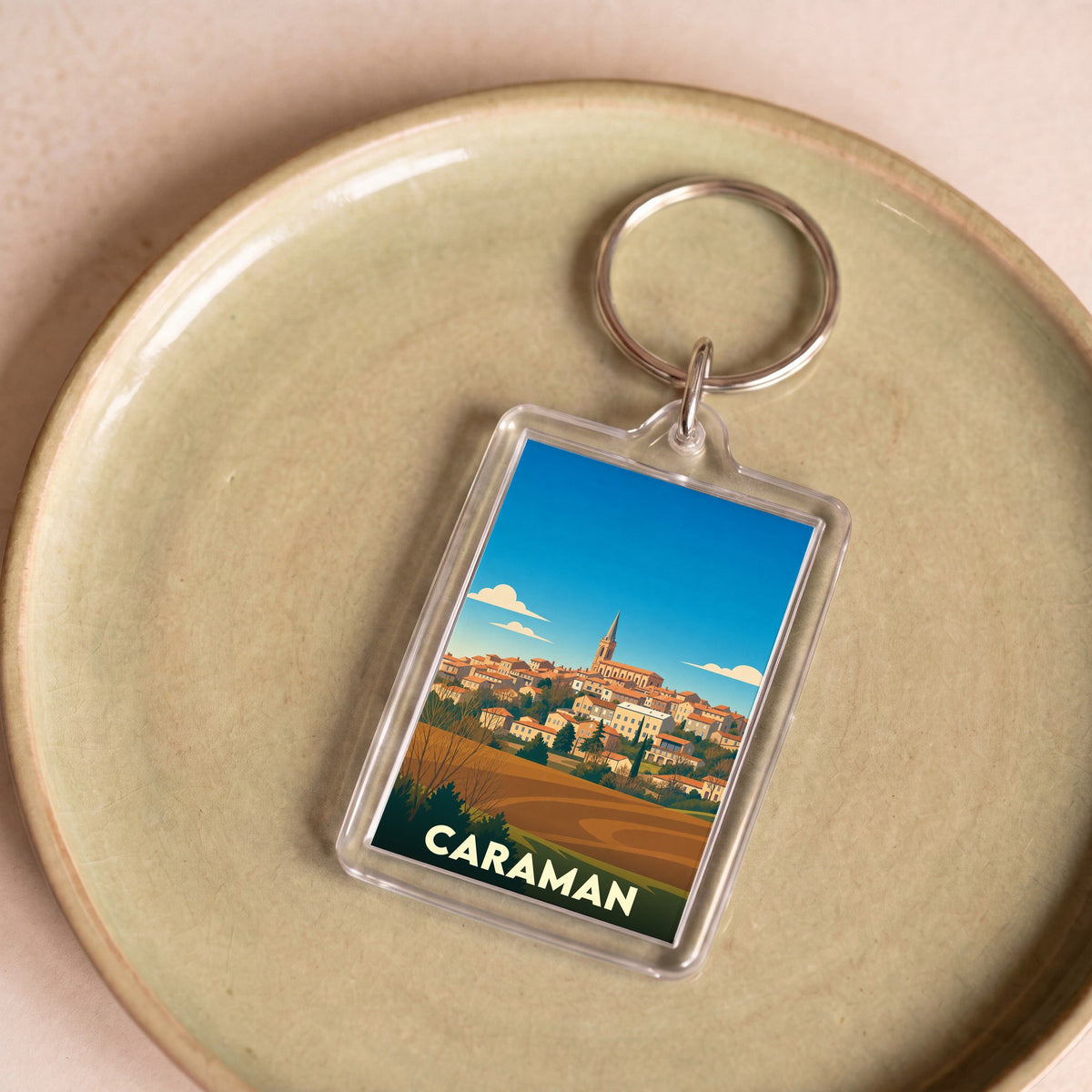 Porte-clés souvenir de la ville de Caraman avec une illustration stylisée.