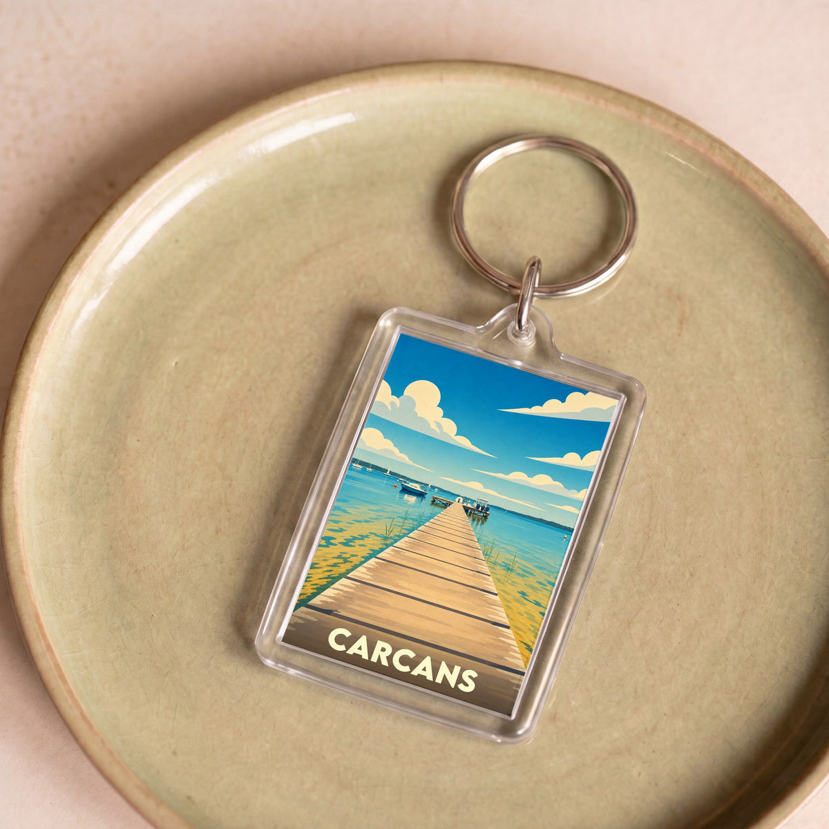 Porte-clés souvenir de la ville de Carcans avec une illustration stylisée d'un ponton sur le lac.