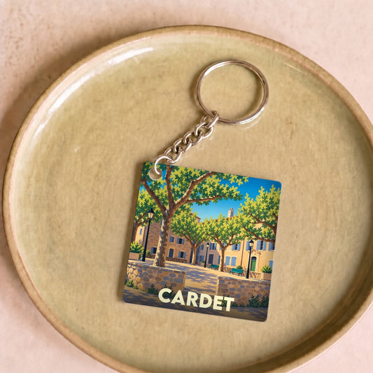 Porte-clés souvenir de la ville de Cardet avec une illustration stylisée d'une place ensoleillée.