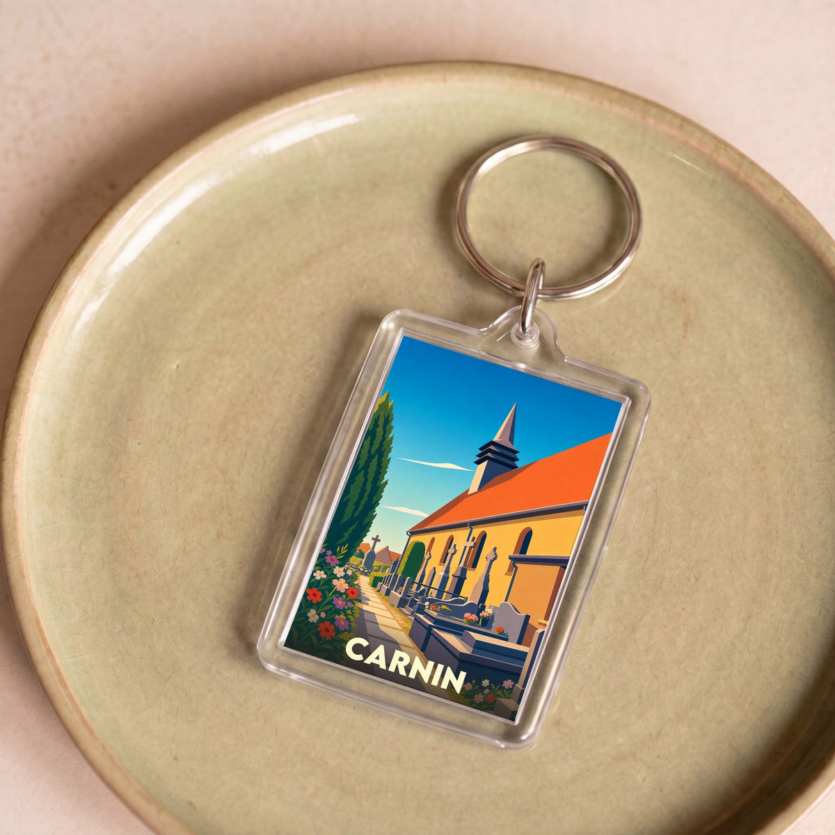 Porte-clés souvenir de la ville de Carnin avec une illustration stylisée de son église et de son cimetière.