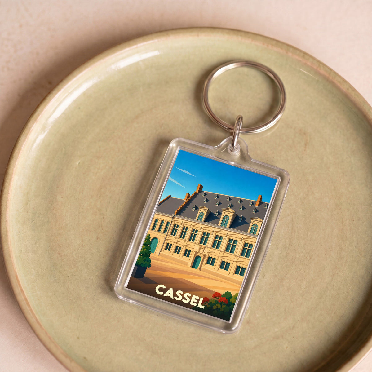 Porte-clés souvenir de la ville de Cassel avec une illustration stylisée d'un bâtiment historique.