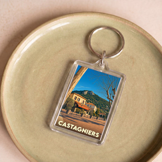Porte-clés souvenir de la ville de Castagniers avec une illustration stylisée d'un paysage ensoleillé.