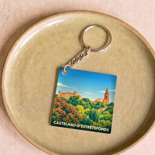 Porte-clés souvenir de la ville de Castelnau-d'Estrétefonds avec une illustration stylisée de son paysage urbain.