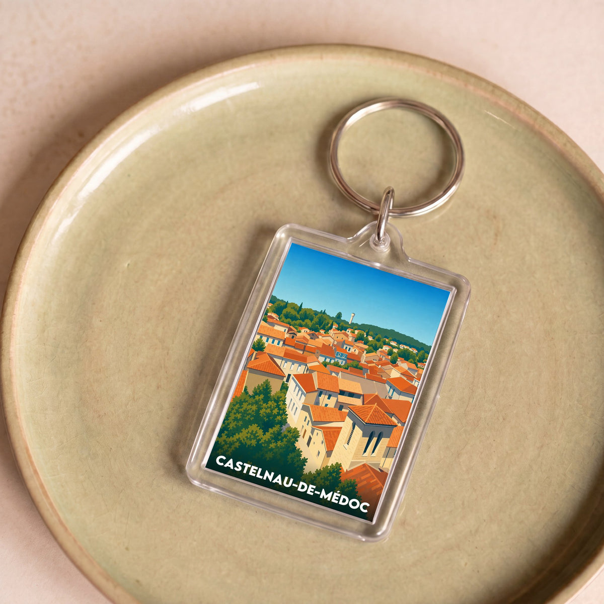 Porte-clés souvenir de la ville de Castelnau-de-Médoc avec une illustration stylisée.
