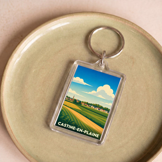 Porte-clés souvenir de la ville de Castine-en-Plaine avec une illustration stylisée de paysages ruraux.