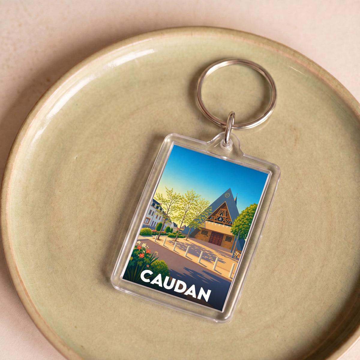 Porte-clés souvenir de la ville de Caudan avec une illustration stylisée.