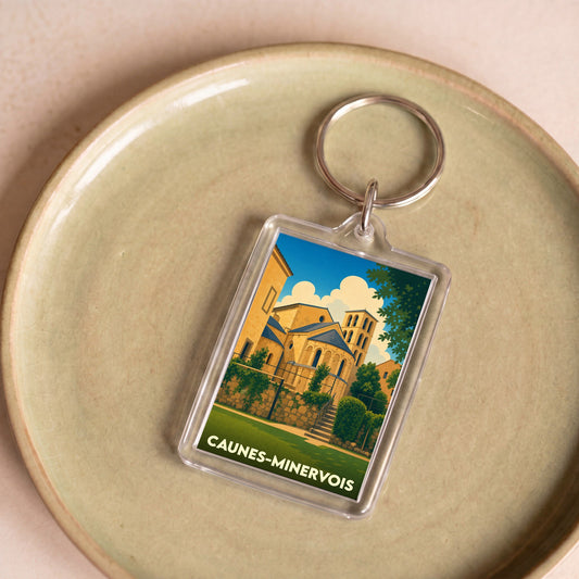 Porte-clés souvenir de la ville de Caunes-Minervois avec une illustration stylisée de son abbaye.