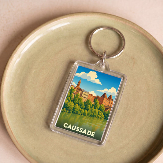 Porte-clés souvenir de la ville de Caussade avec une illustration stylisée.
