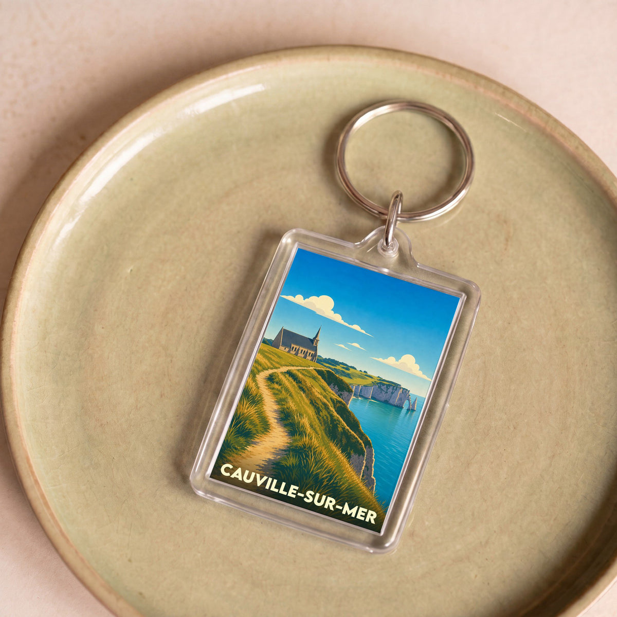 Porte-clés souvenir de la ville de Cauville-sur-Mer avec une illustration stylisée de ses falaises.