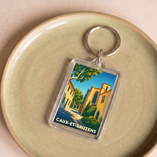 Porte-clés souvenir de la ville de Caux-et-Sauzens avec une illustration stylisée.