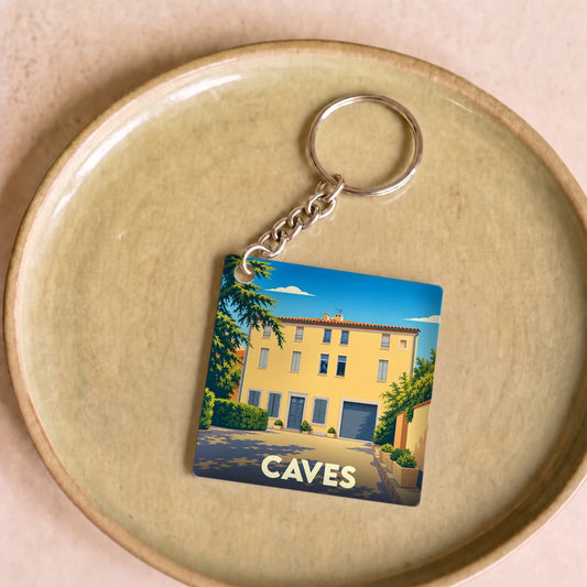 Porte-clés souvenir de la ville de Caves avec une illustration stylisée d'une maison ensoleillée.
